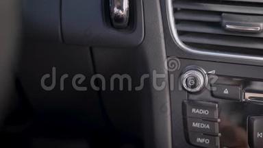 在框架中，一个人的手和一个汽车音频音量旋钮。 司机或乘客调整音乐音量水平..